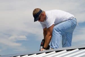 man uses drill on roof